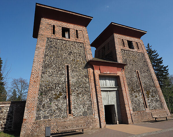 Zwei Backsteintürme. Sie sind über einen Durchgang miteinander verbunden.