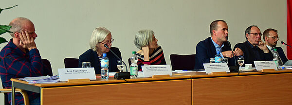 Sechs Frauen und Männer sitzen in einem Podium.