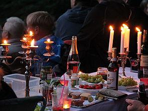 Ein gedeckter Picknicktisch mit flackernden Kerzen. 