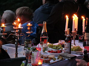 Ein gedeckter Picknicktisch mit flackernden Kerzen. 