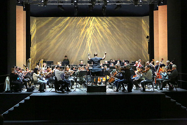 Blick auf eine Bühne. Auf der Bühne spielt die Staatskapelle.