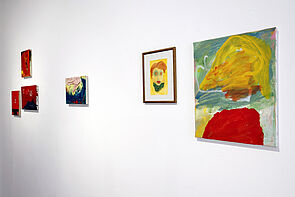 Kleine, mittlere und ein großes Bild in der Ausstellung. Das große zeigt ein Porträt.
