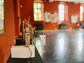 Auf einem Holzpferd sitzt ein Holzreiter. Arme, Beine und Gelenke sind aus Draht.