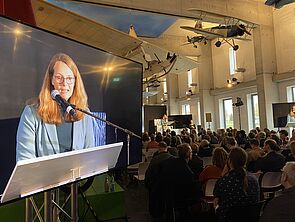 Die Rede von Ministerin Bettina Martin wird auf einem Bildschirm übertragen. 