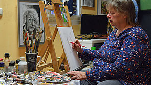 Martina Kriedel sitzt an einer Staffelei und zeichnet.