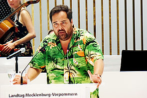 Schauspieler Martin Neuhaus steht im Plenarsaal am Rednerpult. 
