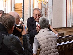 Günther Uecker wird von Gästen im Dom begrüßt.