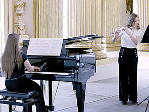 Zwei Jugendliche spielen Klavier und Querflöte.
