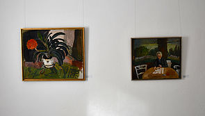An einer Wand hängen zwei dunkle Gemälde.