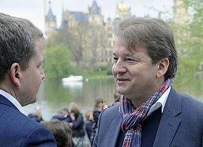 Rico Badenschier und Lars Tietje stehen einander gegenüber und reden. Im Hintergrund steht das Schweriner Schloss.
