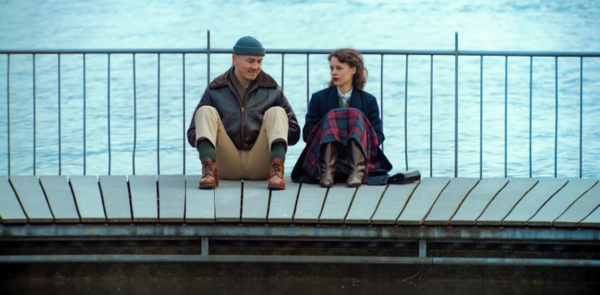 Ein Mann und eine Frau sitzen auf dem Boden einer Brücke.