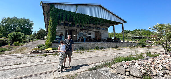 Lydia Klammer und Tino Bittner vor einer Terrasse einer Industriehalle.