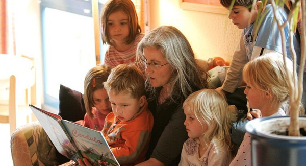 Eine Frau liest Kindern aus einem Buch vor.