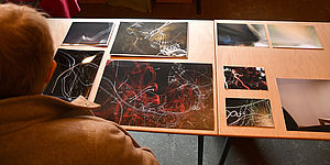 Auf einem Tisch liegen neun abstrakte Bilder. 