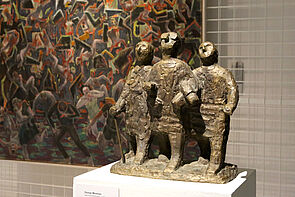 Eine Skulptur mit drei Personen, die sich unterhaken.