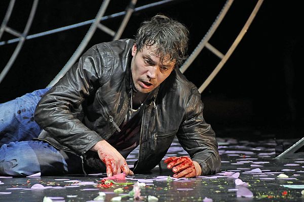 Martin Brauer liegt in einer Szene mit blutverschmierten Händen auf der Bühne.