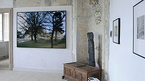 An der Wand hängt ein große Fotografie. Sie zeigt das Schloss. im Vordergrund stehen Bäume.