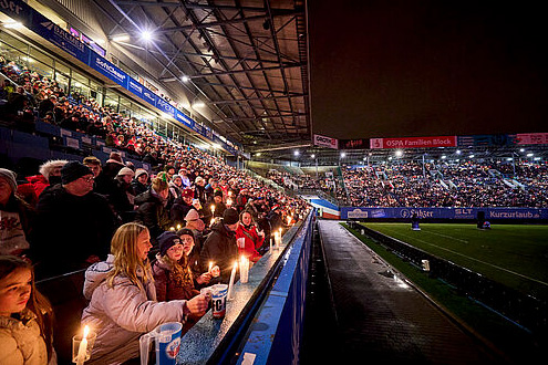 Viele Menschen. Sie stehen in einem Stadion und singen. 