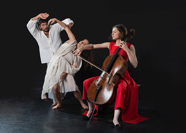 Ein Tanzpaar auf der Bühne. Vor ihnen spielt eine Musikerin Cello.